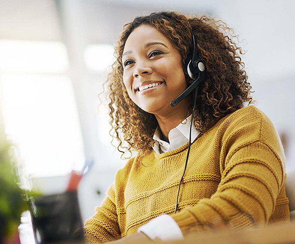 Call center representative wearing a headset and smiling while assisting a caller
